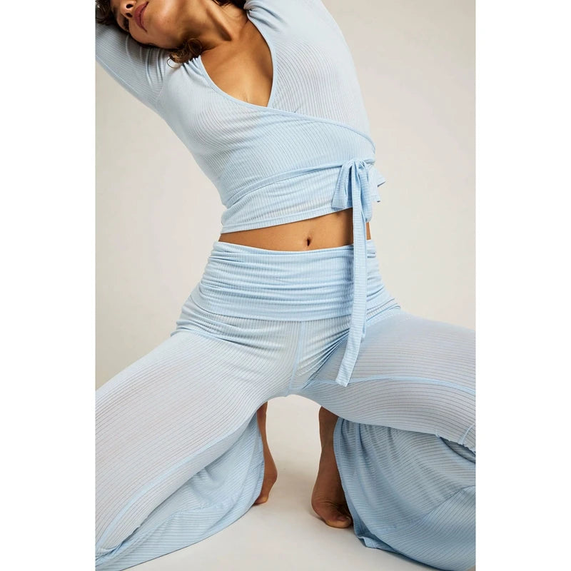 Woman wearing a light blue ribbed outfit on a plain background