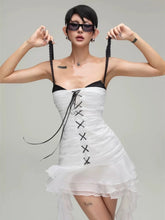 Woman wearing a white dress with black lace details against a gray background