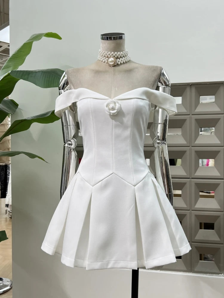 White off-shoulder dress on a mannequin with a pearl necklace against a neutral background