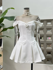 White off-shoulder dress on a mannequin with a pearl necklace against a neutral background