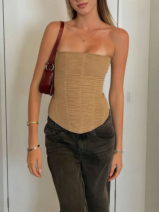 Woman wearing a khaki strapless top and dark jeans, holding a red handbag.