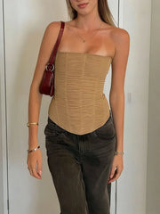 Woman wearing a khaki strapless top and dark jeans, holding a red handbag.