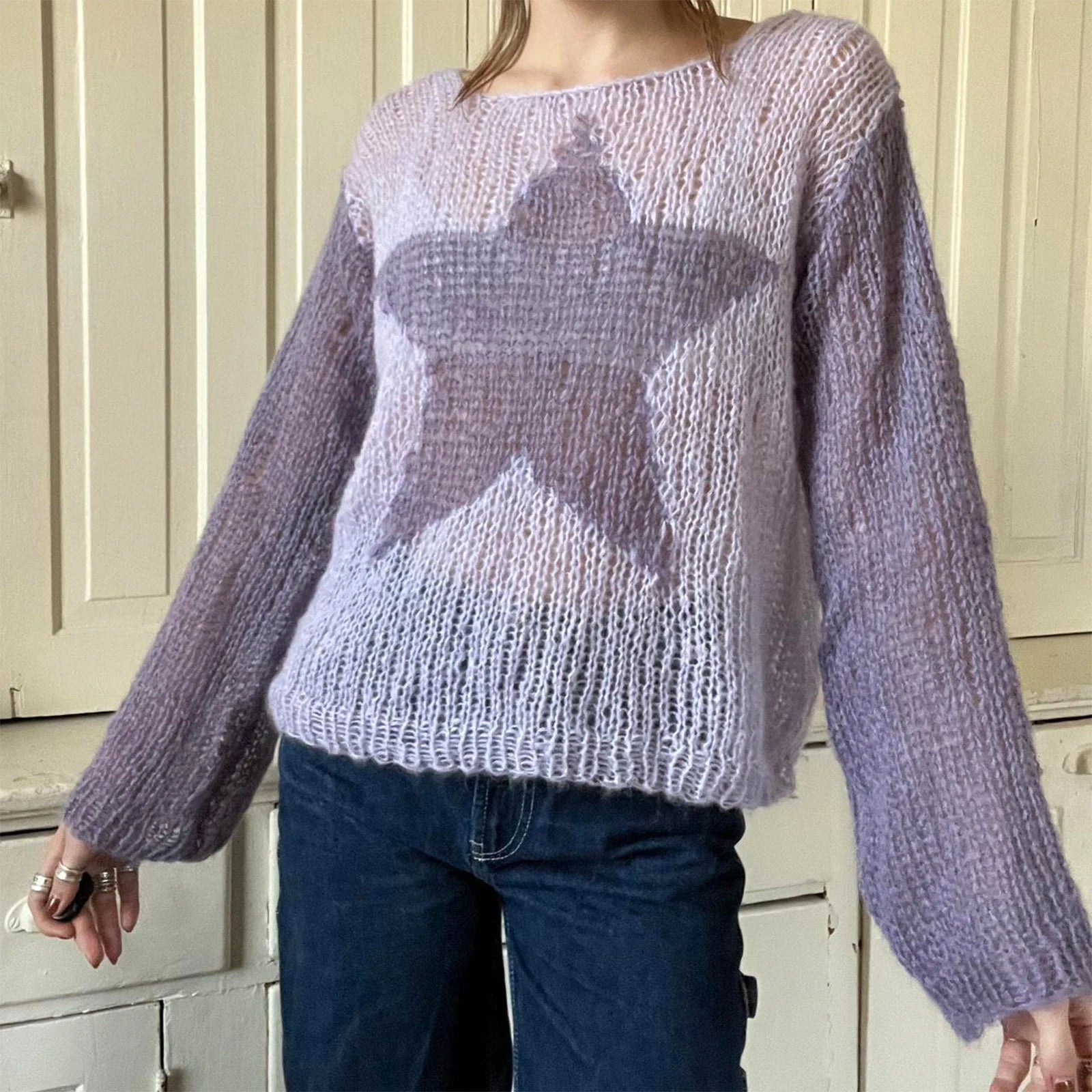 Person wearing a purple sweater with a star design indoors.