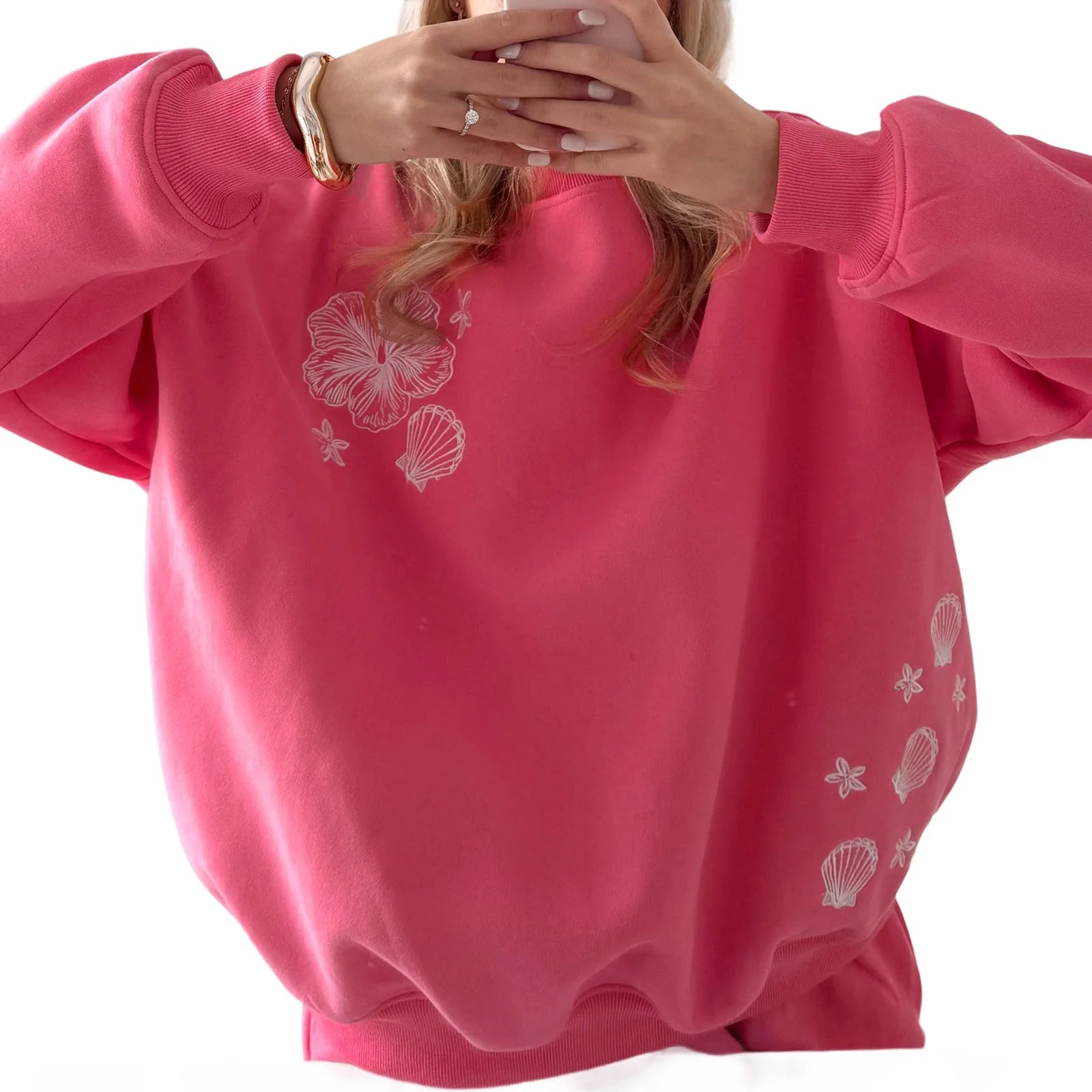 Pink sweatshirt with white shell designs on a white background