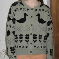 Green cardigan with black floral and duck pattern worn by a person.