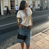 Woman in a white blouse and denim shorts standing on a street