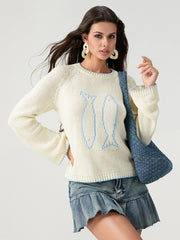 Woman wearing a cream sweater with bunny design and denim skirt, holding a blue bag.