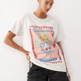 Person wearing a white t-shirt with colorful graphic design on a plain background