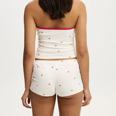 White strapless top and shorts set with red heart patterns on a plain background