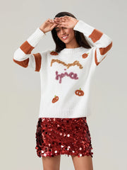 Woman wearing a white sweater with Halloween-themed designs and a red sequin skirt on a plain background