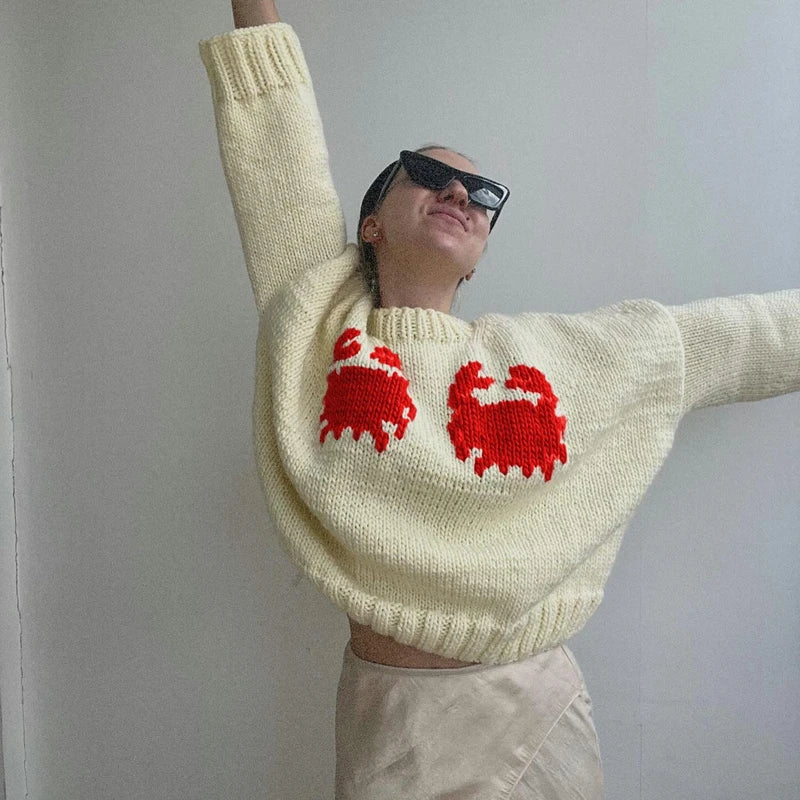 Person wearing a cream sweater with red patterns against a plain background