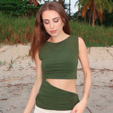 Woman wearing a green sleeveless top with cut-out design on a beach.