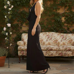 Woman in a black dress standing outdoors with a floral-patterned couch and plants in the background.