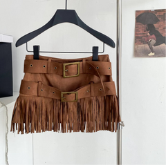 Brown fringe skirt on a hanger with a bag in the background