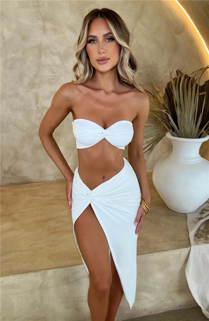 Woman wearing a white strapless top and skirt set against a neutral background.