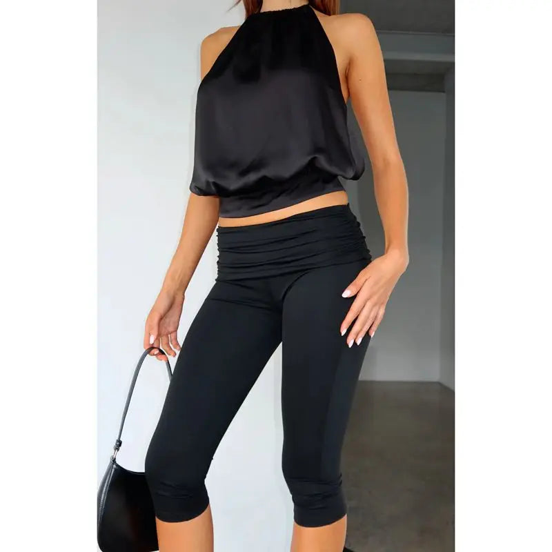 Person wearing a black halter top and Capri leggings