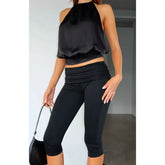 Person wearing a black halter top and Capri leggings
