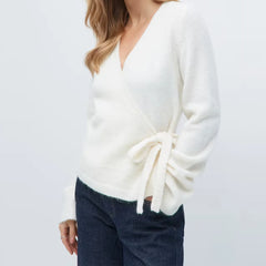 White sweater with tied sleeves worn by a person on a light gray background