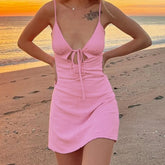 Woman wearing a pink dress on a beach at sunset