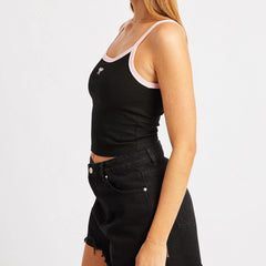 Person wearing a black tank top with white trim and black denim shorts on a light gray background