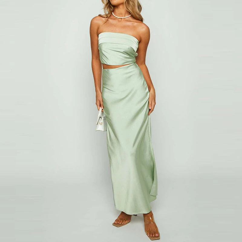 Woman wearing a light green strapless dress with cut-out design on a gray background