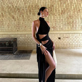 Woman in a black dress standing in a room with a textured wall.