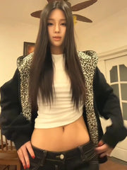 Person wearing a black jacket with leopard print accents, white top, and dark jeans indoors.