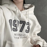 White hoodie with '1973 Weekend in New York' text on a gray background
