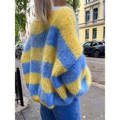 Person wearing a yellow and blue striped sweater on a street.