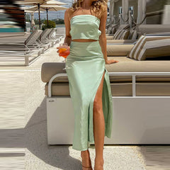 Woman in a light green dress with a high slit standing by a poolside area.
