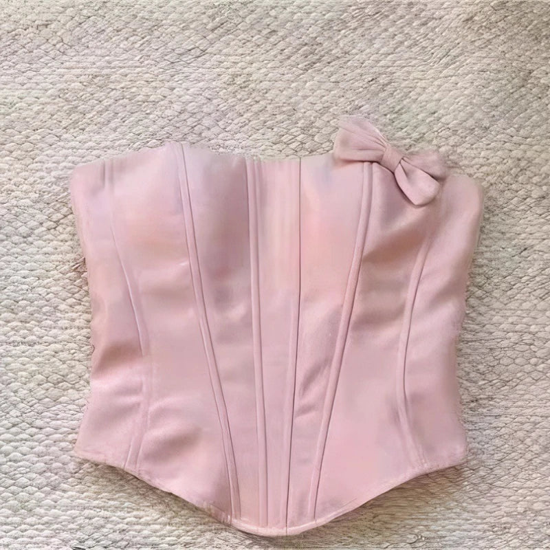 Pink corset with a bow on a textured beige surface