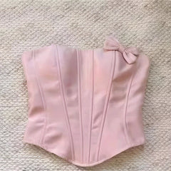 Pink corset with a bow on a textured beige surface