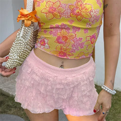 Person wearing a yellow floral top and pink skirt holding a pearl-handled bag.