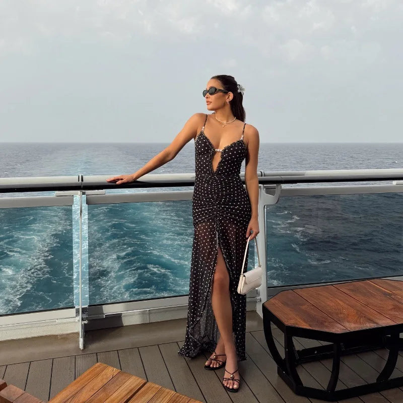 Woman in a black polka dot dress standing on a balcony with ocean view