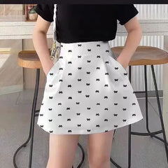 Person wearing a white skirt with black bow pattern in an indoor setting.