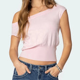 Person wearing a pink off-shoulder top and blue jeans on a light gray background