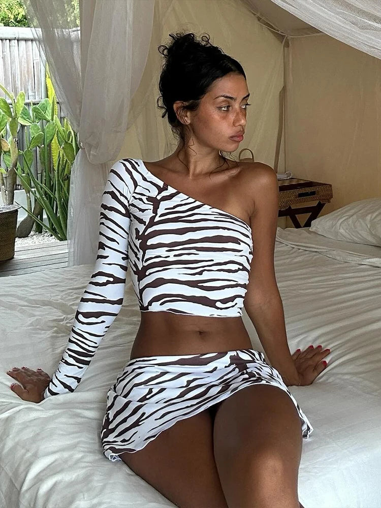 Woman wearing a zebra print outfit sitting on a bed.