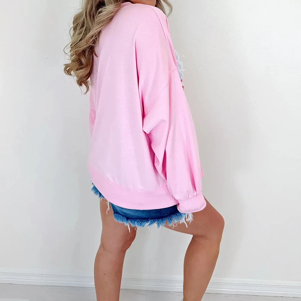 Person wearing a pink over-sized sweatshirt and denim shorts