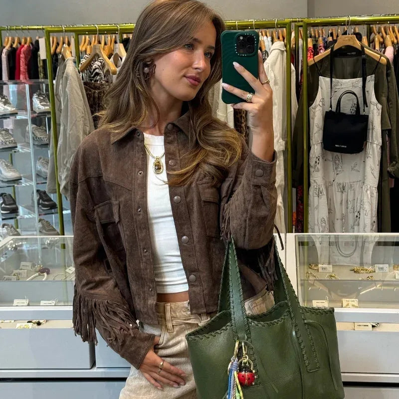 Woman taking a selfie in a clothing store holding a green bag.