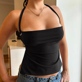 Person wearing a black halter top and blue jeans indoors.