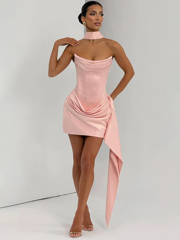Woman wearing a pink strapless dress with a draped design on a plain background