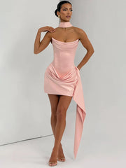 Woman wearing a pink strapless dress with a draped design on a plain background