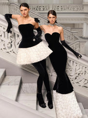 Two women in elegant black and white dresses standing on a staircase.