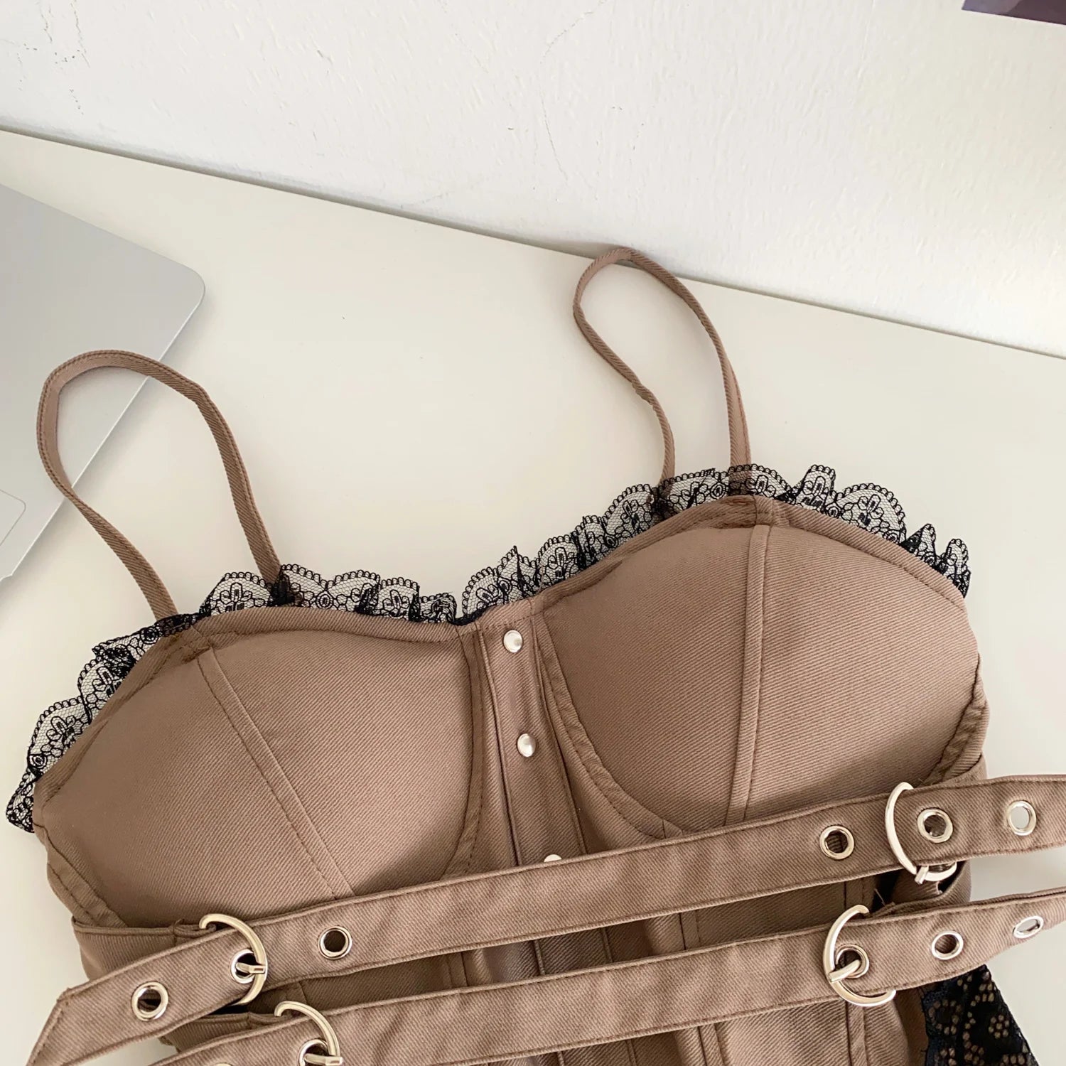 Brown bra with lace trim and garter straps on a white surface