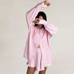 Person wearing a pink oversized shirt against a plain background