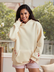 Woman wearing a light-colored hoodie with heart designs outdoors