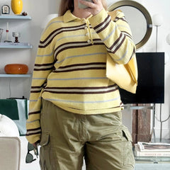 Person wearing a yellow striped sweater and khaki pants taking a mirror selfie.