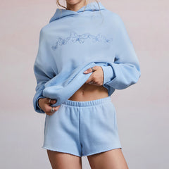 Person wearing a light blue hoodie and shorts set on a plain background