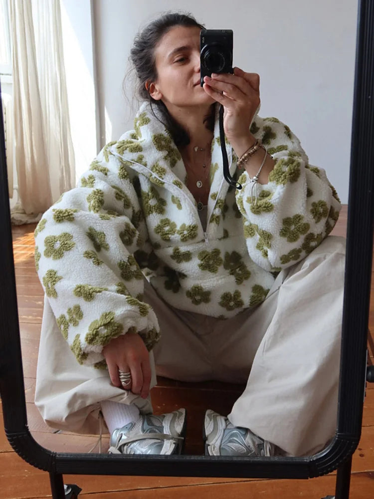 Person wearing a white and green floral outfit sitting on a chair.