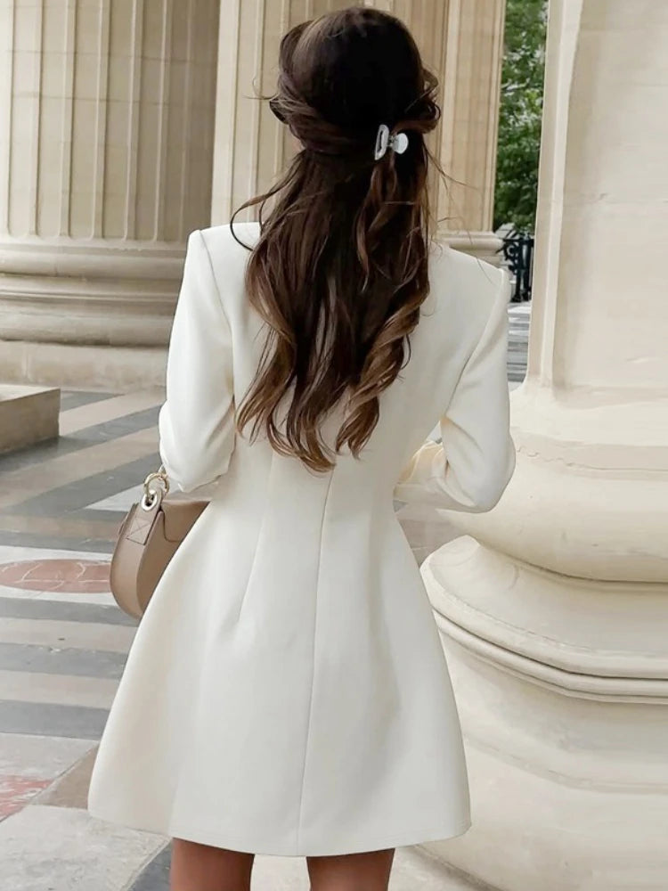 Woman in a white coat standing in front of classical architecture